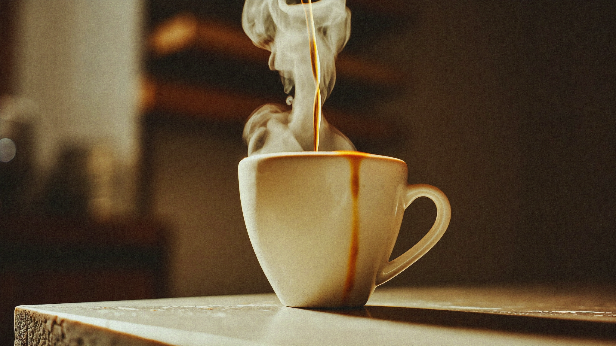Espresso hældes i en langsom stråle ned i en mat keramikkop på en råstensdisk